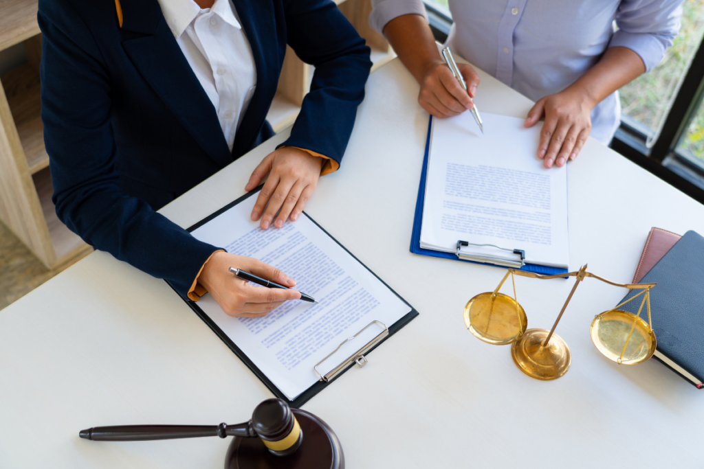 Two professionals in business attire sitting at a desk with a paper and pen.